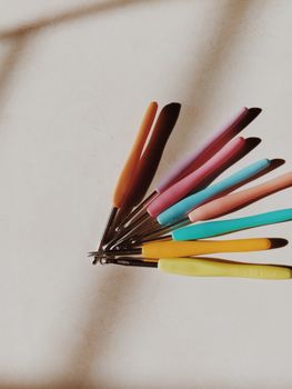 A set of colorful crochet hooks with shadow casting on a white surface, creating a warm and inviting craft scene.