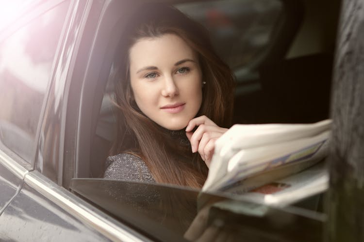 Young Woman With Newspaper In Car