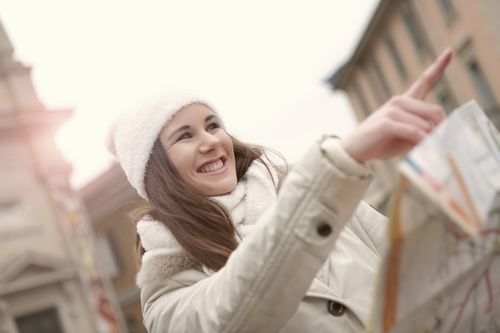 Free Cheerful young woman using map while looking for historical sightseeing and pointing direction Stock Photo