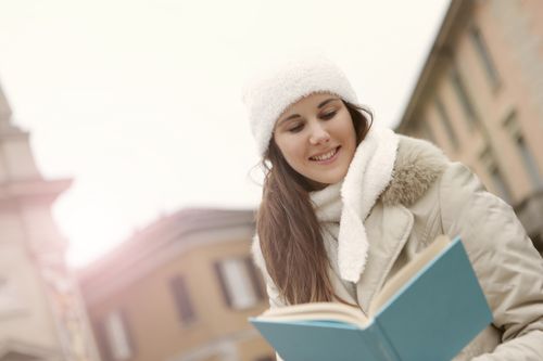 Free From below of content young female in warm clothes standing on city street and enjoying interesting story Stock Photo