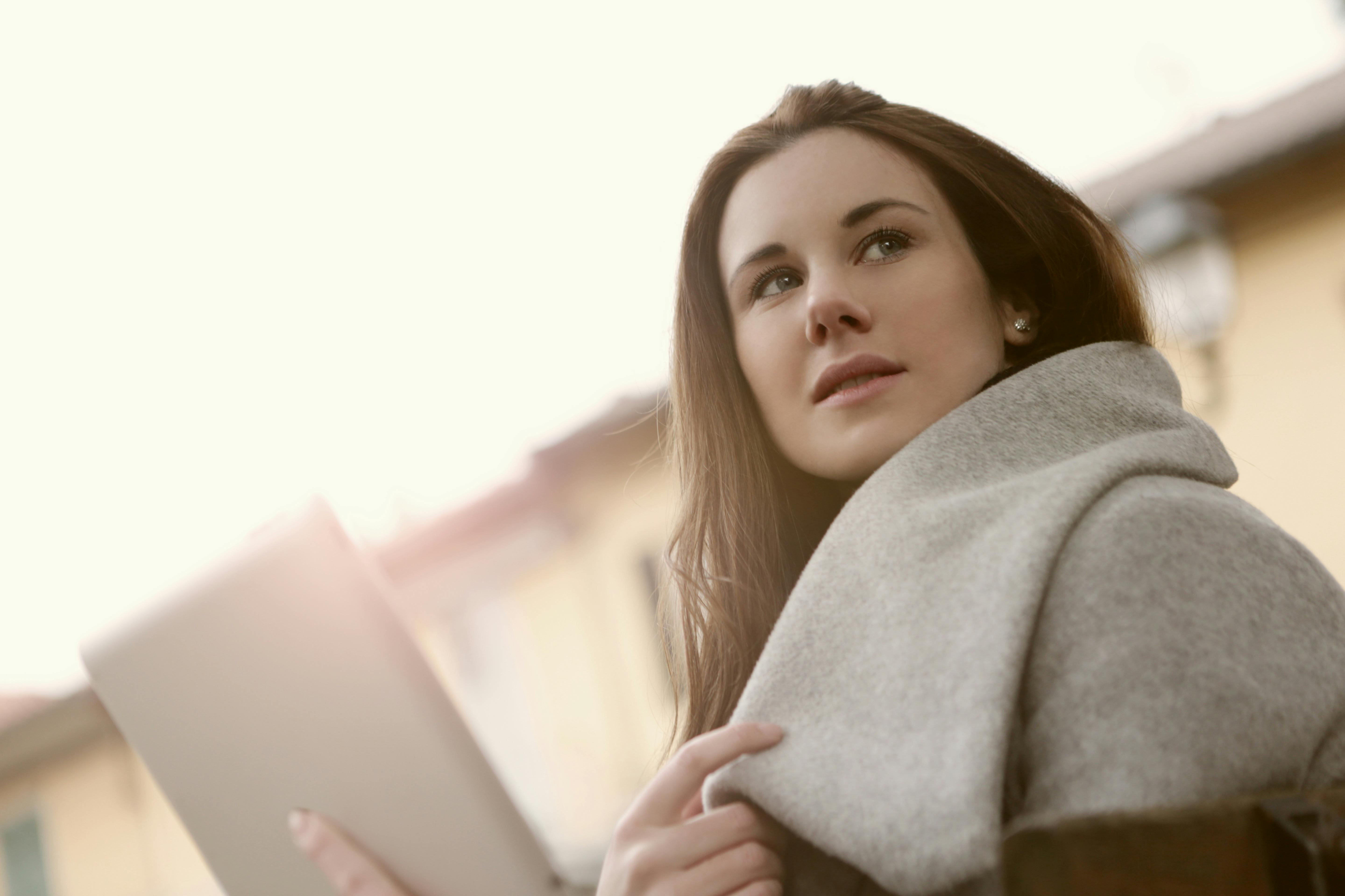 woman in gray hoodie sweater holding a silver tablet