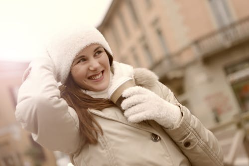 Smiling Woman in White Coat Wearing White Knitted Gloves