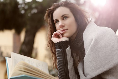 Pensive Woman in Gray Coat Holding Book