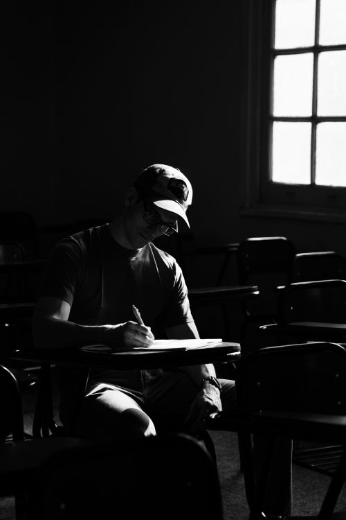 Free A student studying alone in a dark, atmospheric classroom setting. Stock Photo