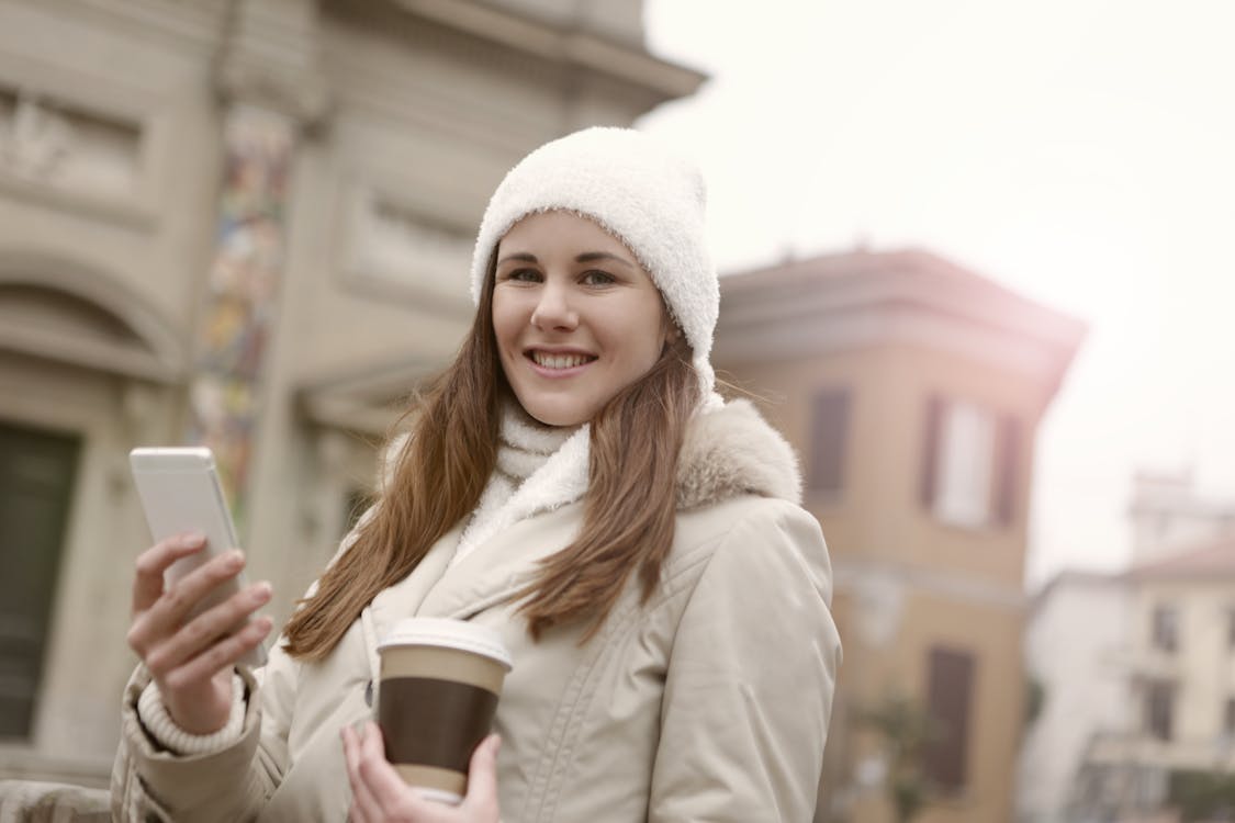 Woman in White Knit Cap Holding Brown Disposable Cup