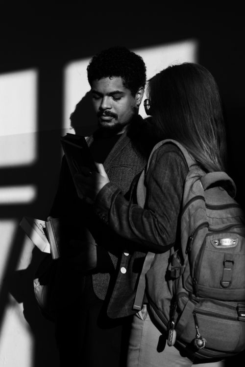 Free A black and white photo of two adults studying together, casting shadows on the wall. Stock Photo