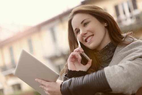 Frau Im Grauen Langarmhemd, Das Silbernes I Pad Und Handy Hält