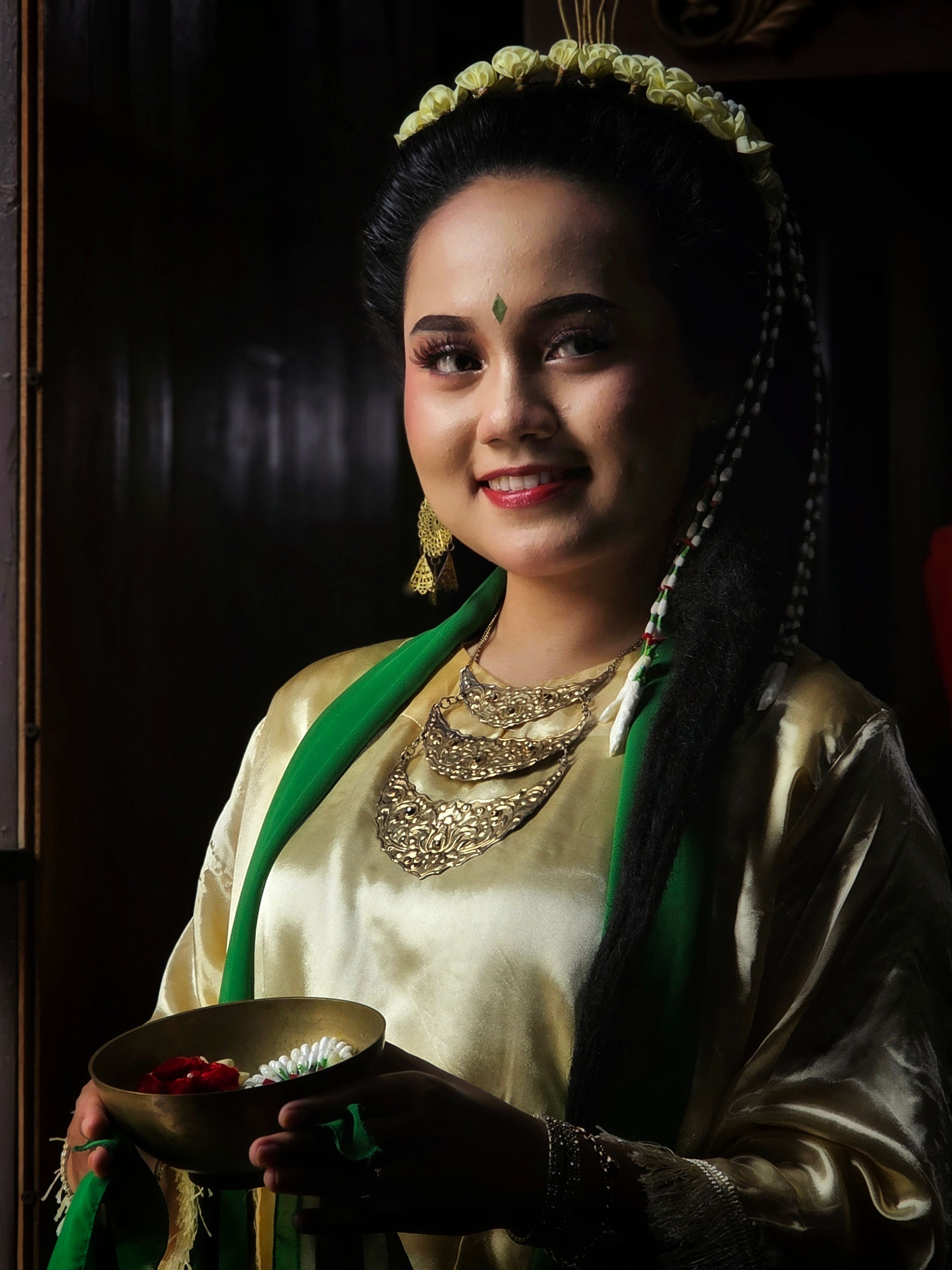 Portrait of a woman in traditional Indonesian dress holding a bowl, showcasing rich cultural heritage.