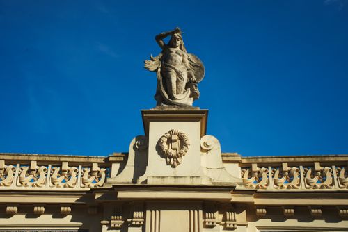 Free A historic architectural statue adorns a building in Warsaw under a bright blue sky. Stock Photo