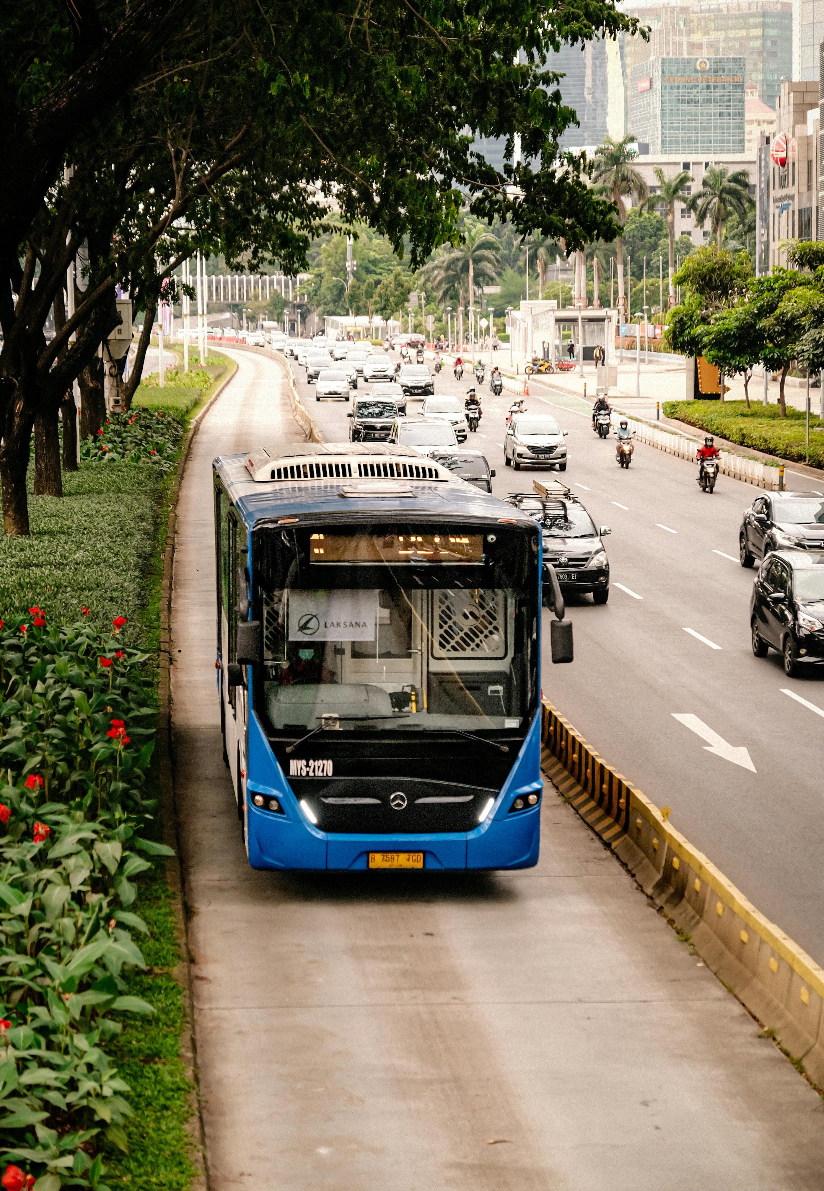 A modern bus travels in a dedicated lane in Jakarta, Indonesia, showcasing urban mobility infrastructure.