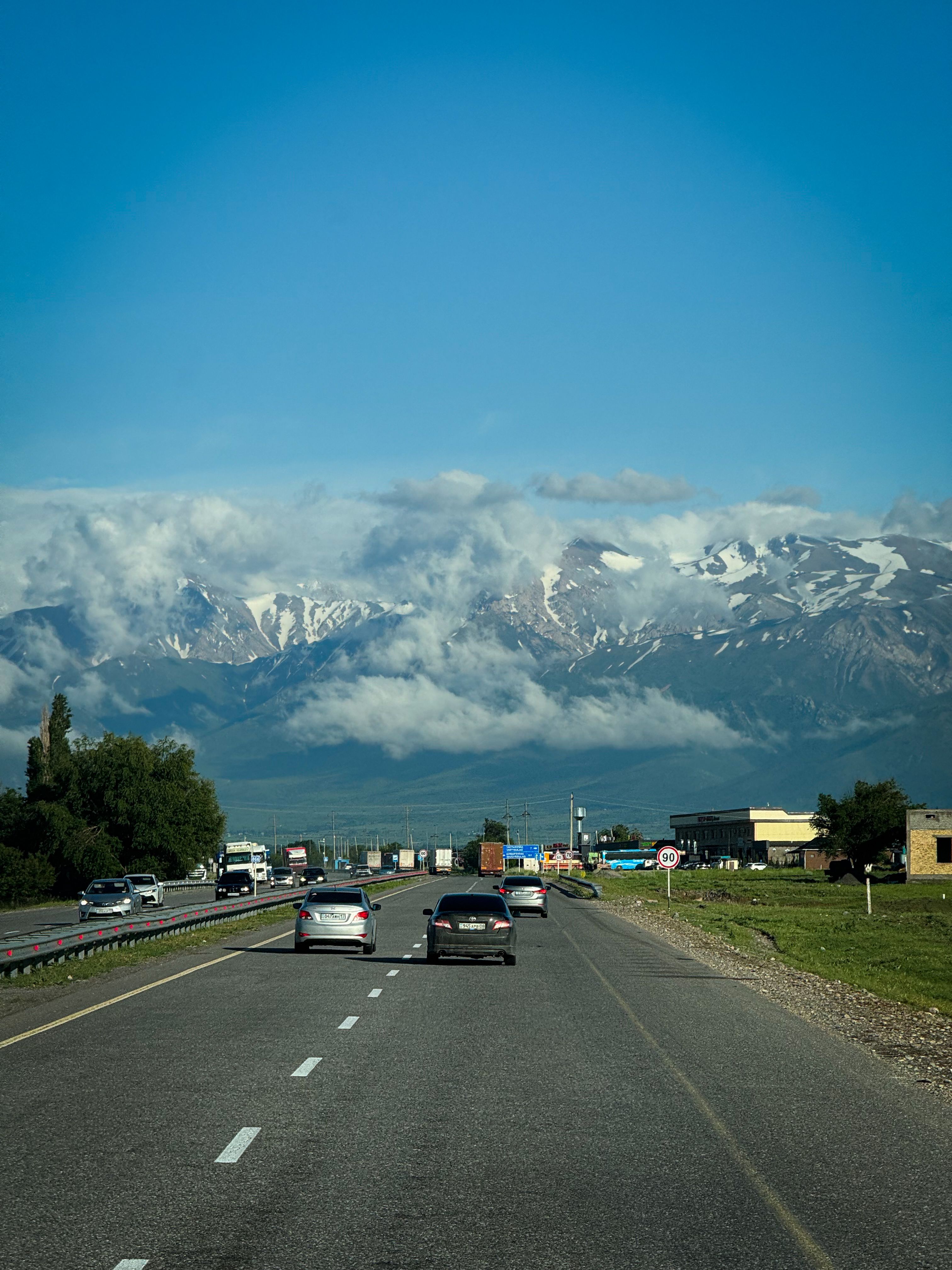 Cars driving on a highway with a stunning view of snow-capped mountains and clear blue sky.