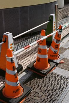 Orange traffic cones with Japanese text seen on a street in Tokyo, Japan.