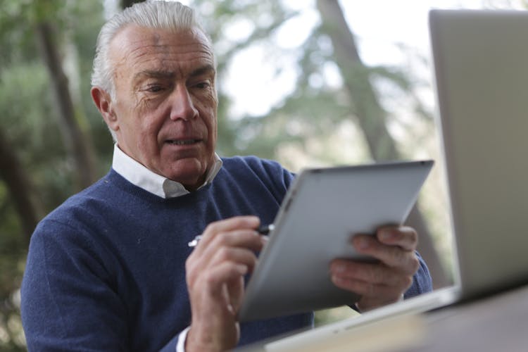 Man In Blue Sweater Holding Silver Ipad