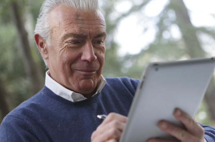 Man In Blue Sweater Holding Silver Ipad