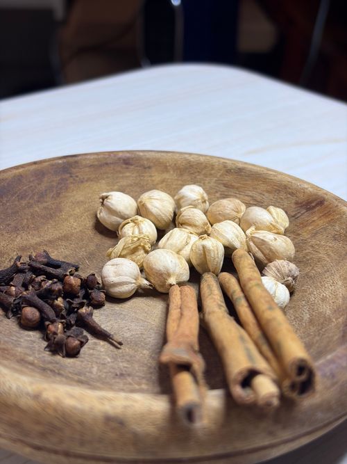 Free Detailed view of spices including cloves, cardamom, and cinnamon on a wooden plate. Stock Photo