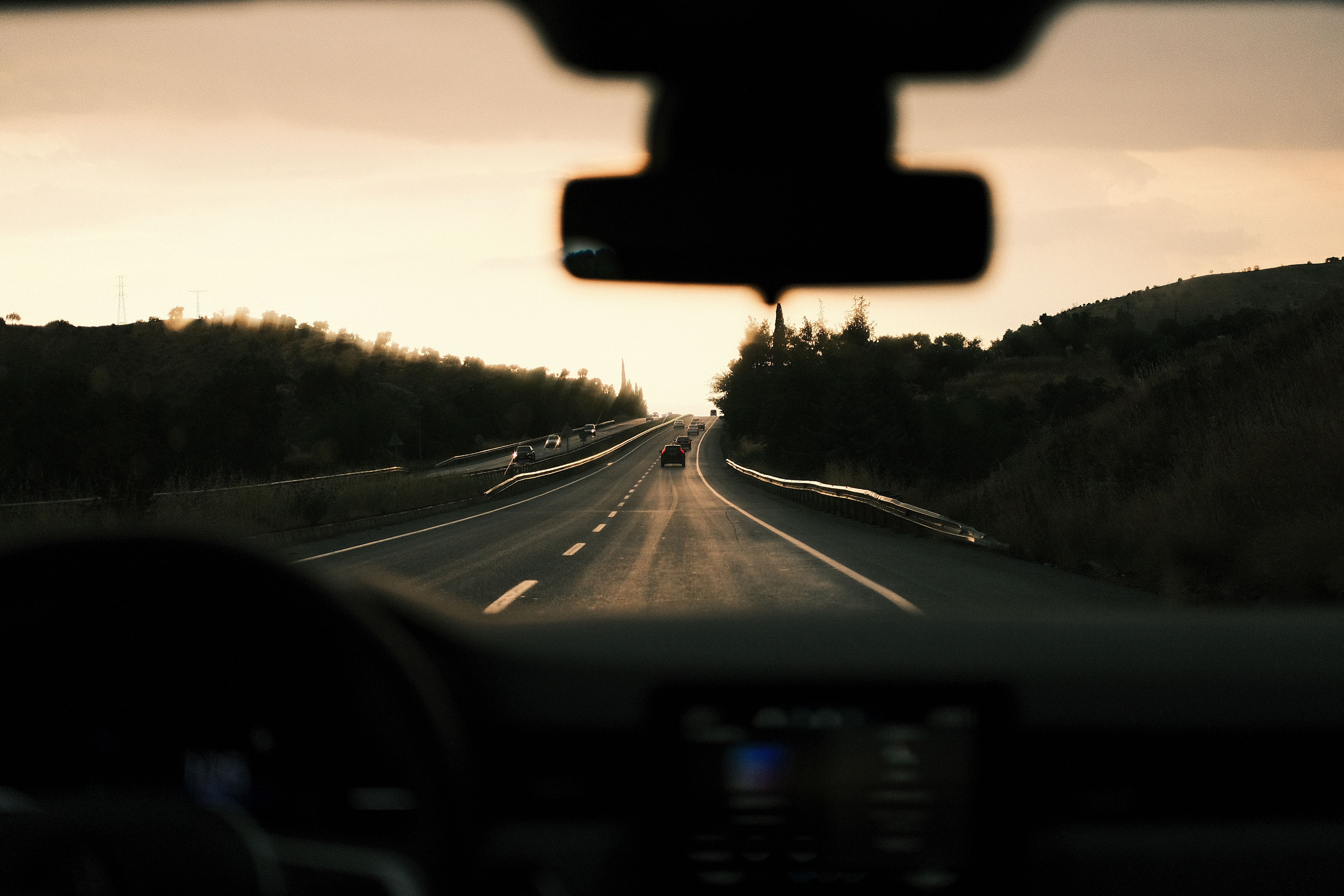 A picturesque view from inside a car driving towards the sunset along a peaceful highway.