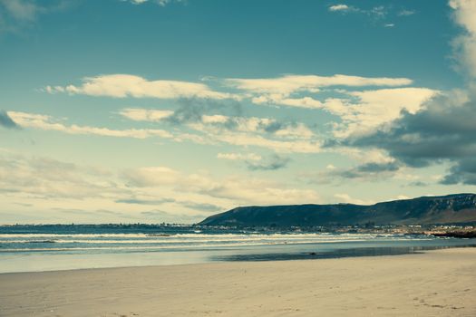 Peaceful beach with scenic mountains under a vibrant sky, perfect for nature lovers.