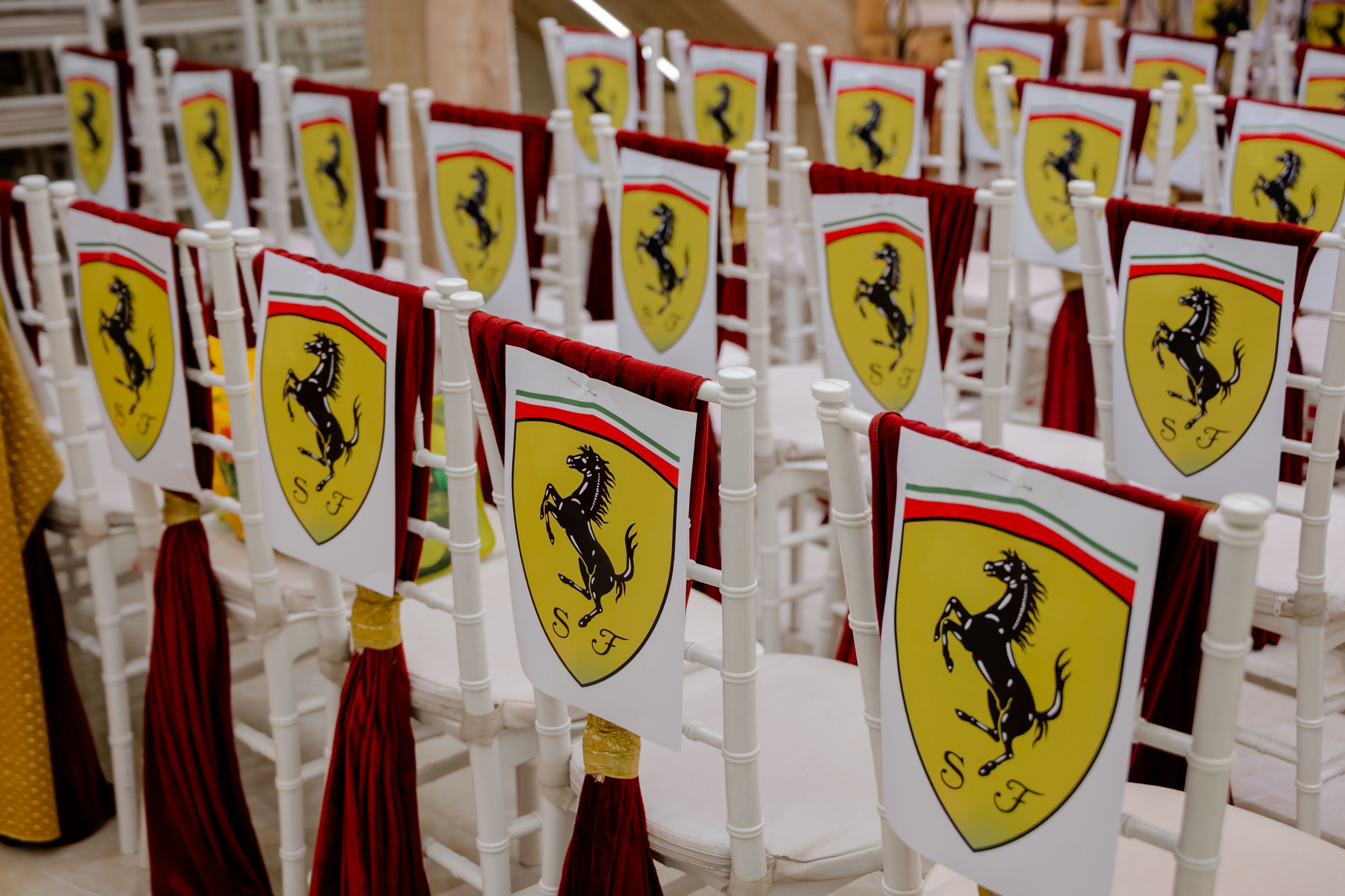 White chairs with Ferrari logos create a lavish atmosphere at an indoor event in India.