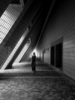 A lone figure walks through a striking tiled corridor in Kowloon, Hong Kong.