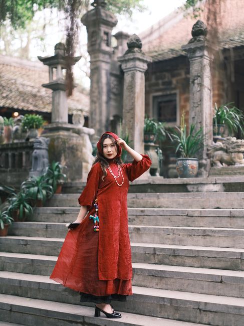 A woman poses in a red dress on stone steps at a historic temple.