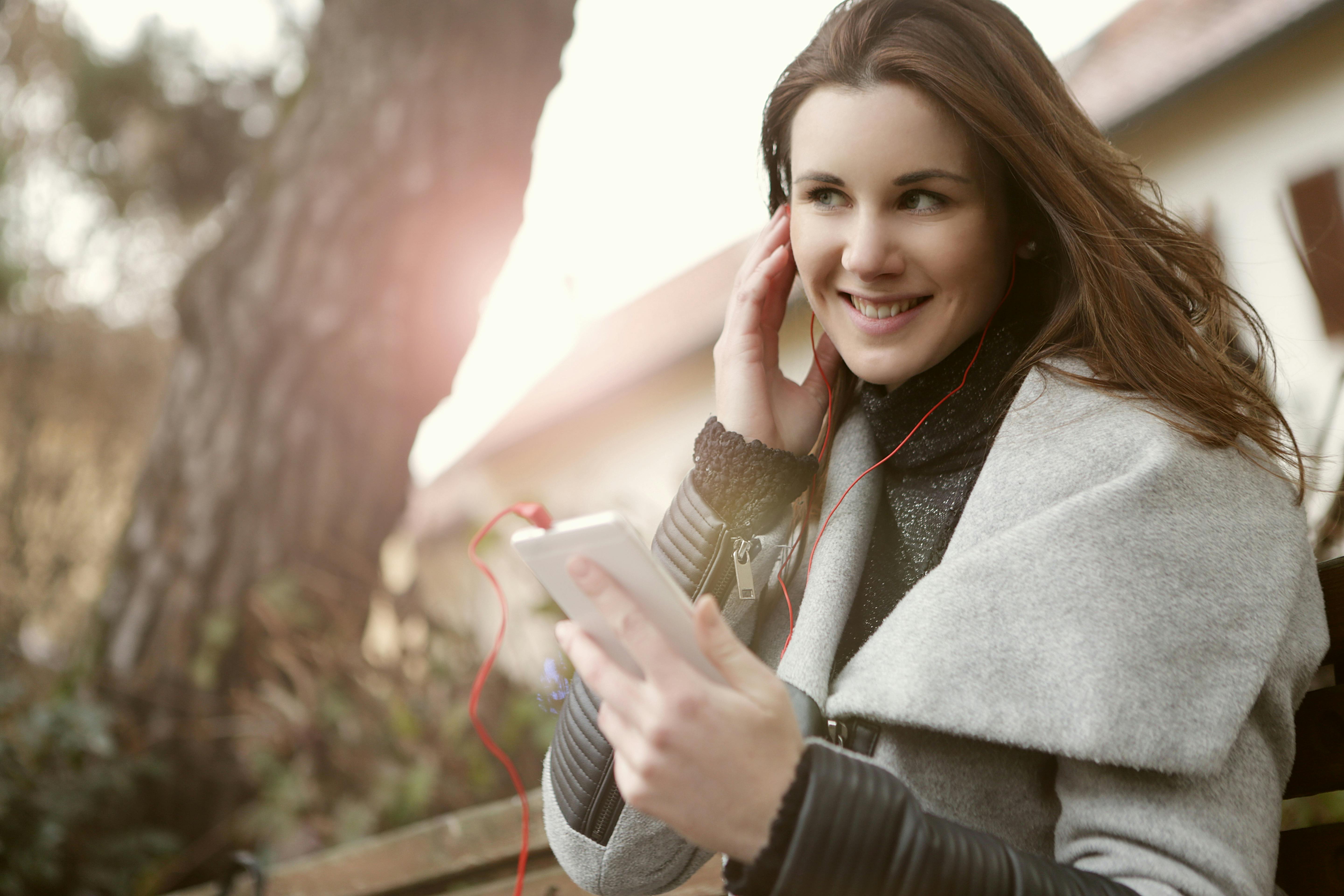 woman in gray coat holding a white smartphone