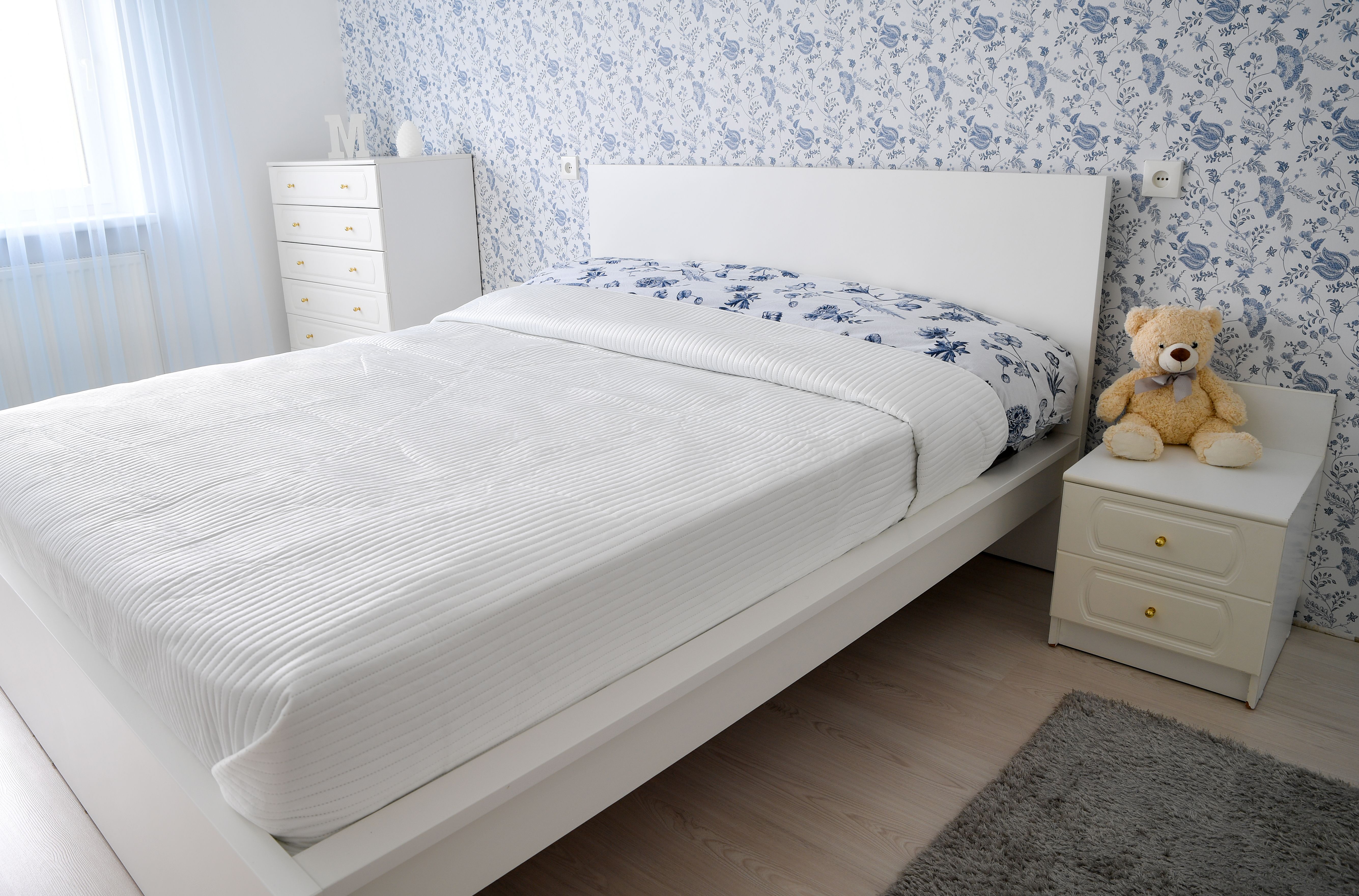 Helles Schlafzimmer mit weißer Raufasertapete, Abdeckvlies und Malerrolle beim Raufasertapete ausbessern und Streichen