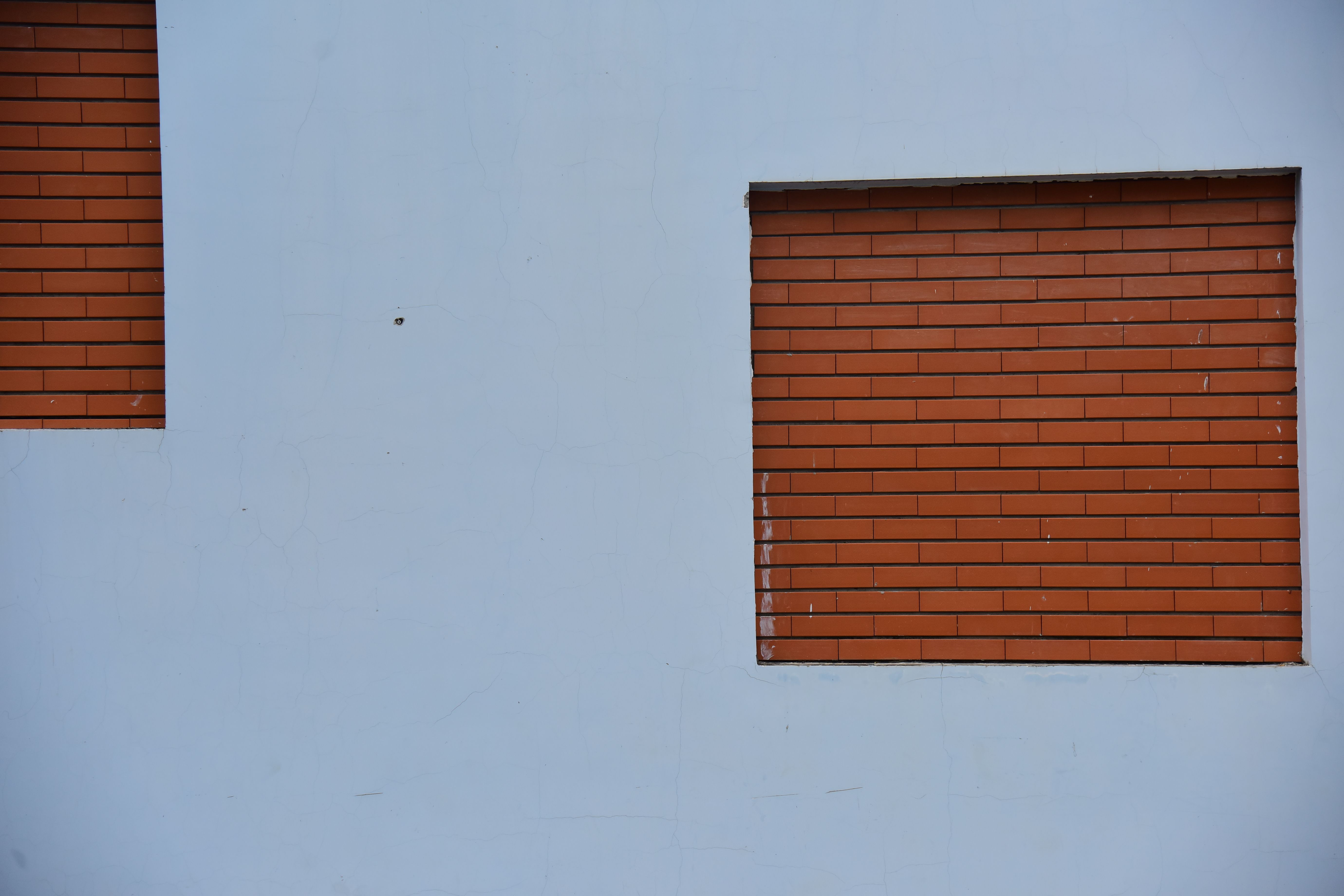 Fotomural Diseño sencillo de incrustaciones de ladrillo sobre una pared blanca, que muestra un estilo arquitectónico minimalista.