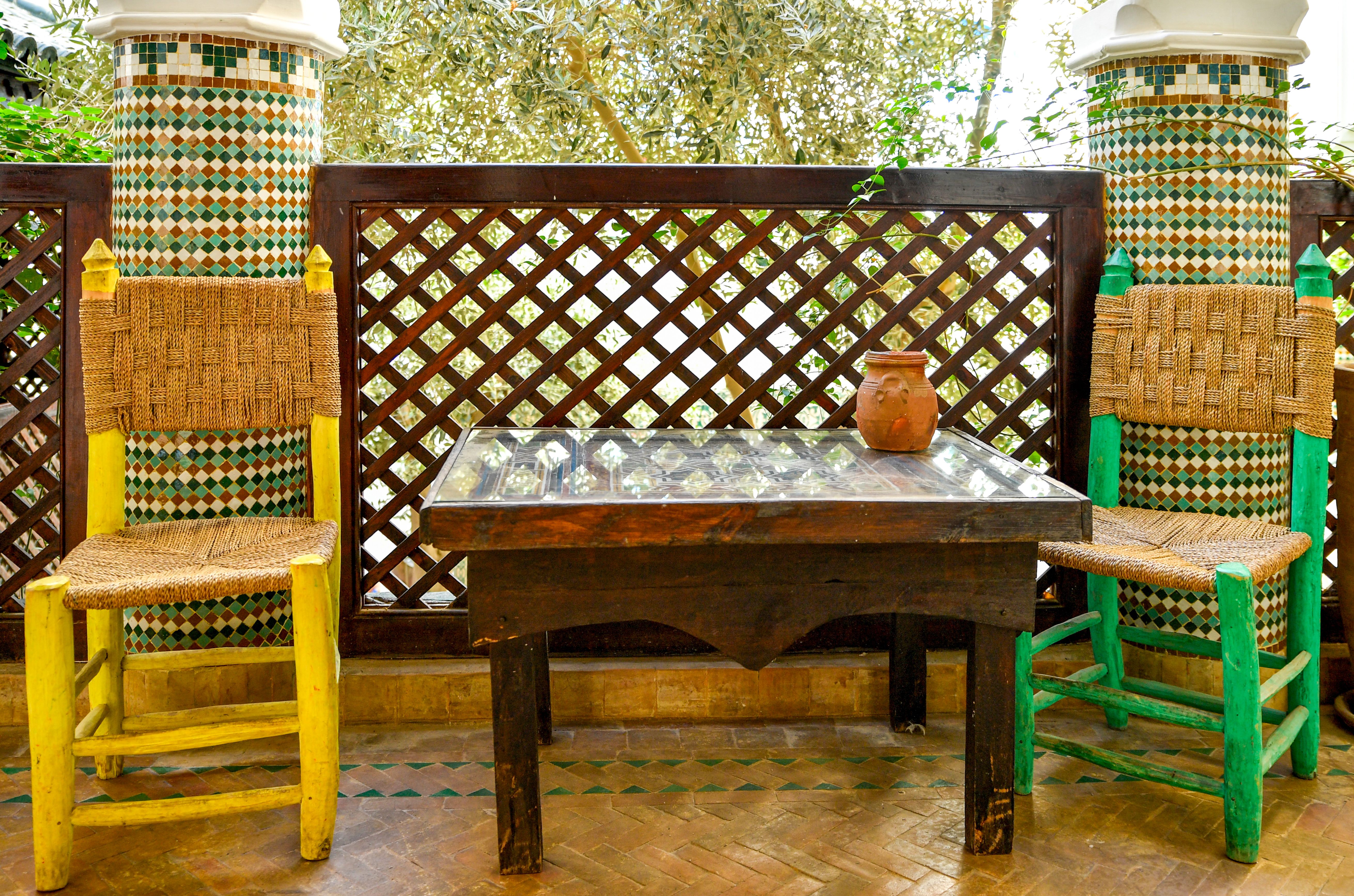 Colorful courtyard with woven chairs and mosaic tiles in Marrakesh, Morocco.
