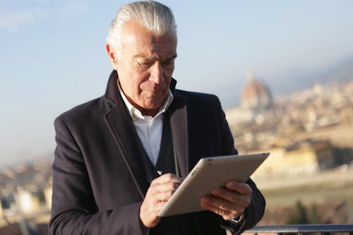 Man in Black Suit Holding Silver Ipad