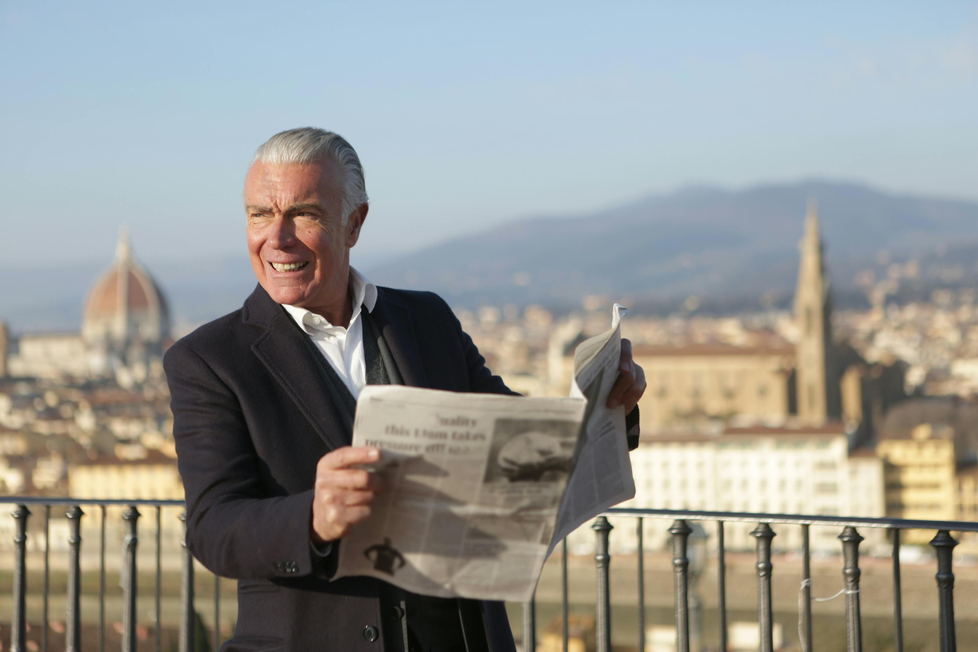 man in black suit jacket holding a newspaper