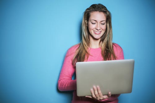 Joven con portátil sonriendo en fondo azul