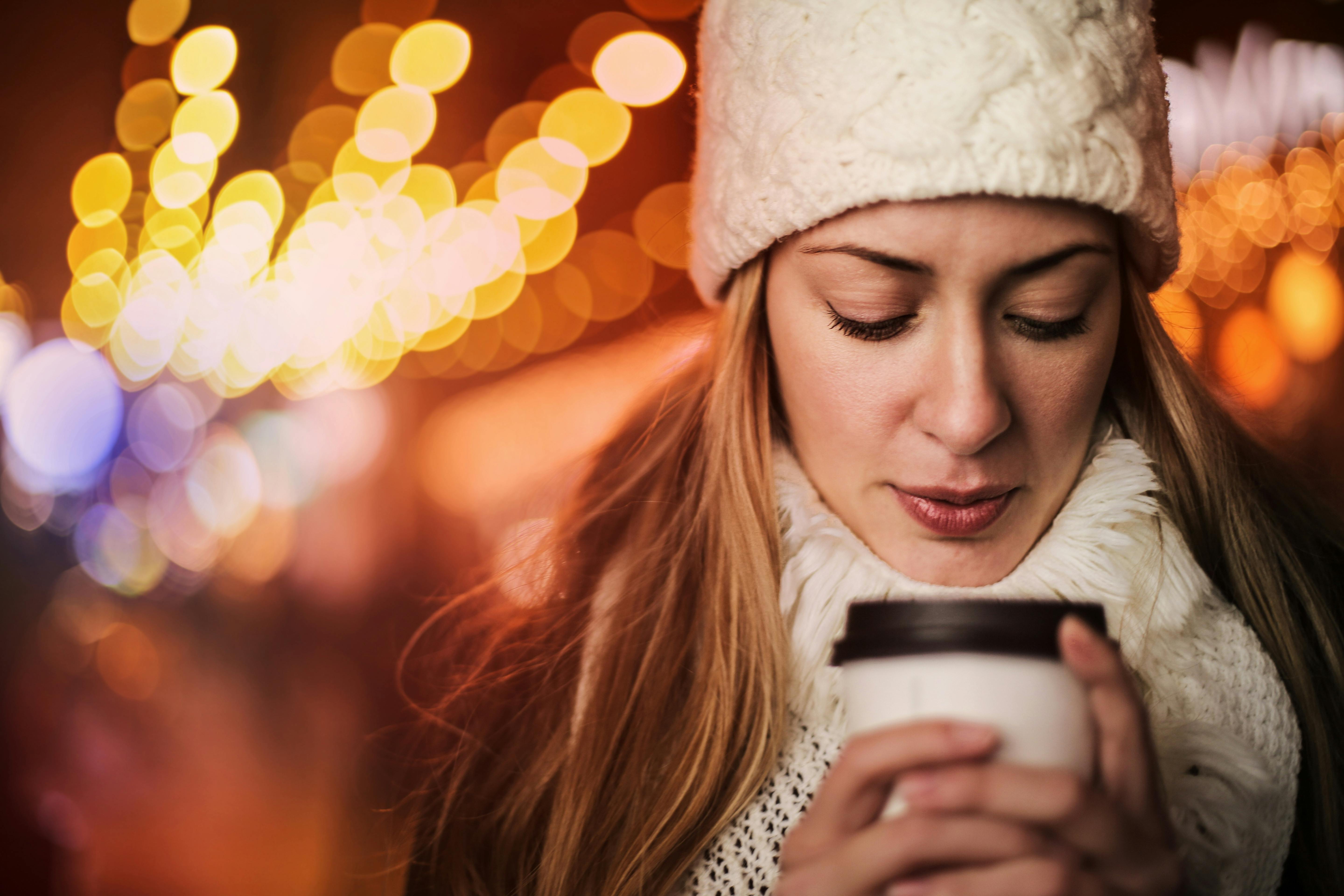 woman with takeaway hot drink on street in cold weather