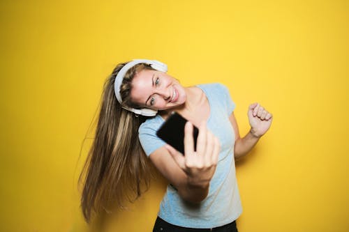 Free Satisfied woman taking selfie on smartphone in studio Stock Photo