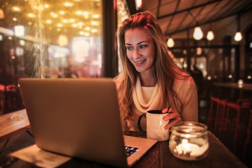 Free Woman Sitting by the Table Using Silver Laptop Stock Photo