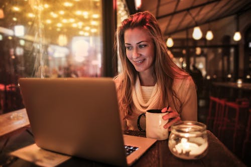 Woman Sitting by the Table Using Silver Laptop