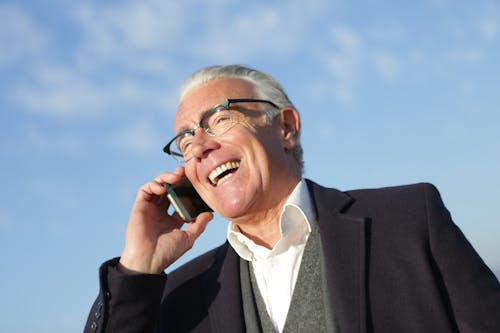 A smiling elderly man on the phone.