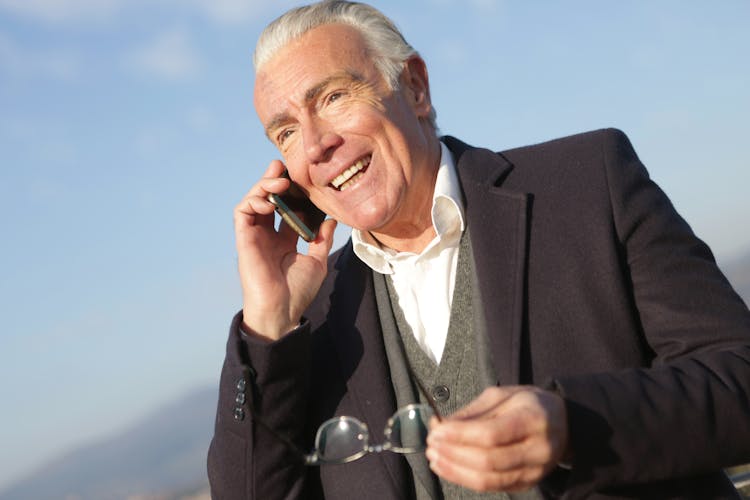 Mature Businessman Having Conversation On Smartphone In City