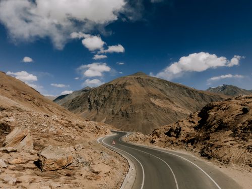 Free Winding road through the rugged landscape of the Himalayas under a clear blue sky. Stock Photo