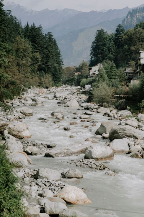Free A tranquil mountain river flowing through lush greenery and rocky terrain. Stock Photo