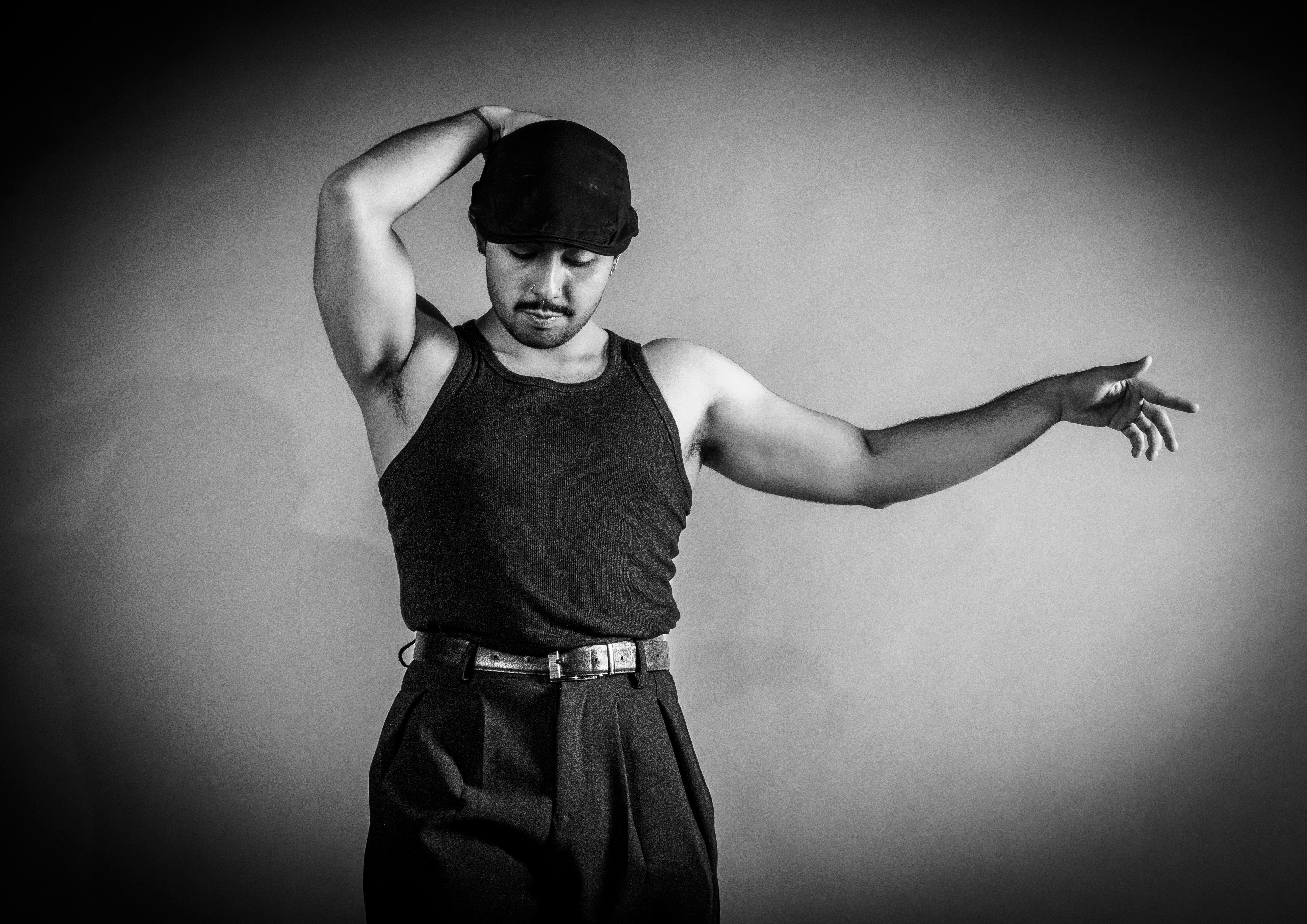 Monochrome portrait of a male dancer in vintage attire, his jawline carved out by hard stage lighting.