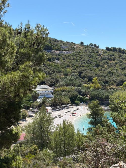 Free Beautiful beach scene with clear blue water surrounded by lush greenery in Split-Dalmatia, Croatia. Stock Photo