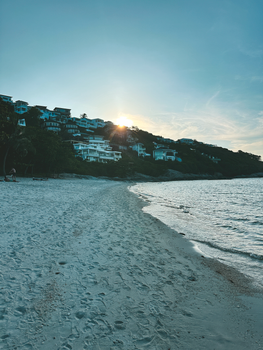 A peaceful beach with hillside villas at sunrise offering a serene coastal view.