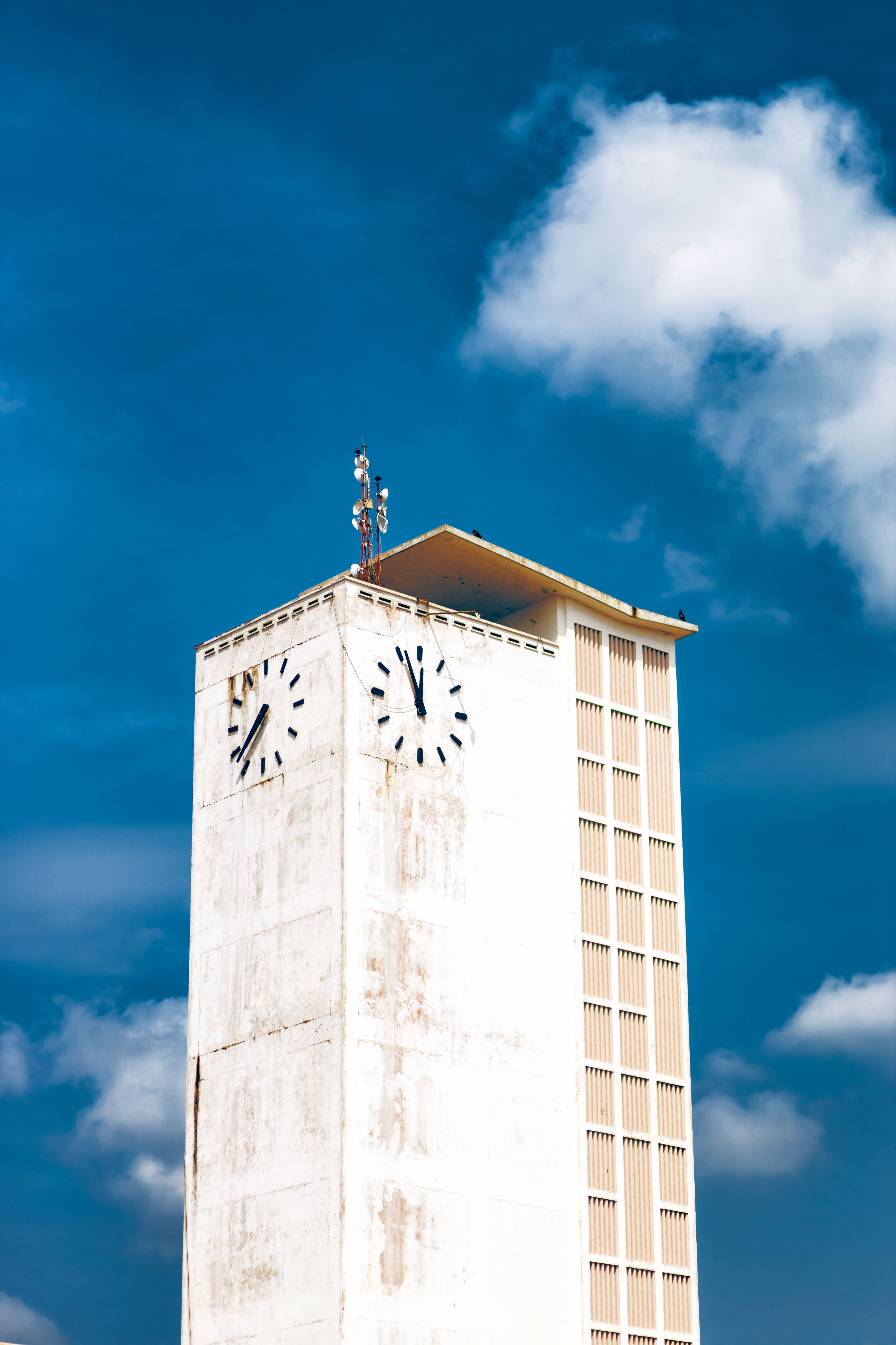 Photograph of the Cocoa House clock tower under a vibrant blue sky in Ibadan, Nigeria.