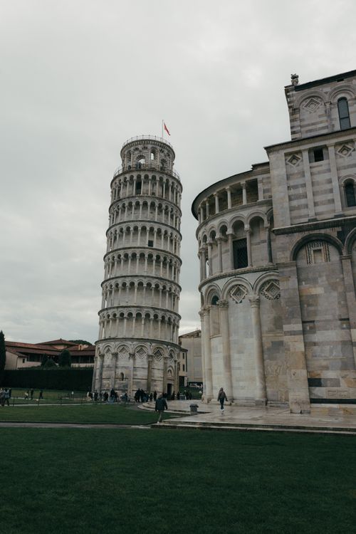 Free Leaning Tower of Pisa with adjacent cathedral in cloudy weather. Stock Photo