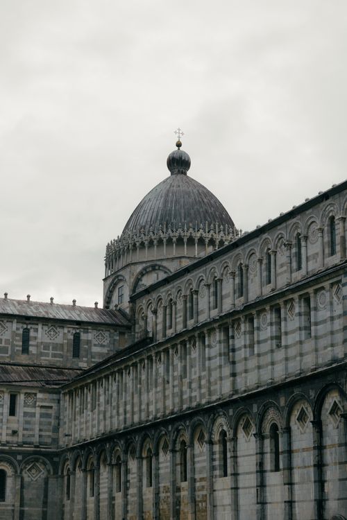 Free A striking view of Pisa Cathedral's dome with intricate architecture under a cloudy sky in Italy. Stock Photo