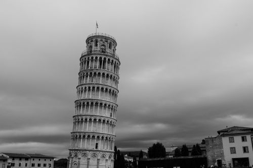 Free Black and white image of the Leaning Tower of Pisa with dramatic clouds. Stock Photo