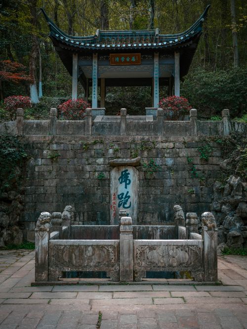 Free A serene Chinese pavilion amidst lush greenery and ancient stone architecture. Stock Photo