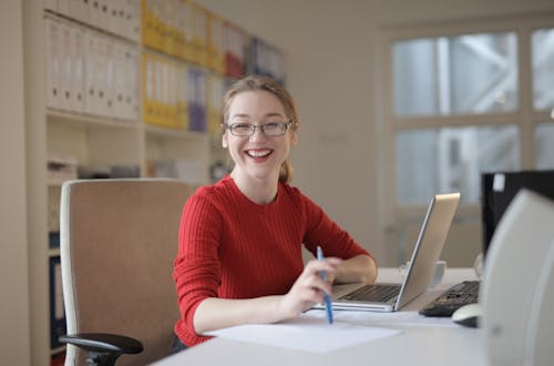 Donna In Maglione Rosso Che Si Appoggia Sulla Tavola Bianca