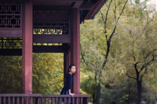 Free A girl gazes from a traditional pavilion in peaceful Kowloon Walled City Park, Hong Kong. Stock Photo