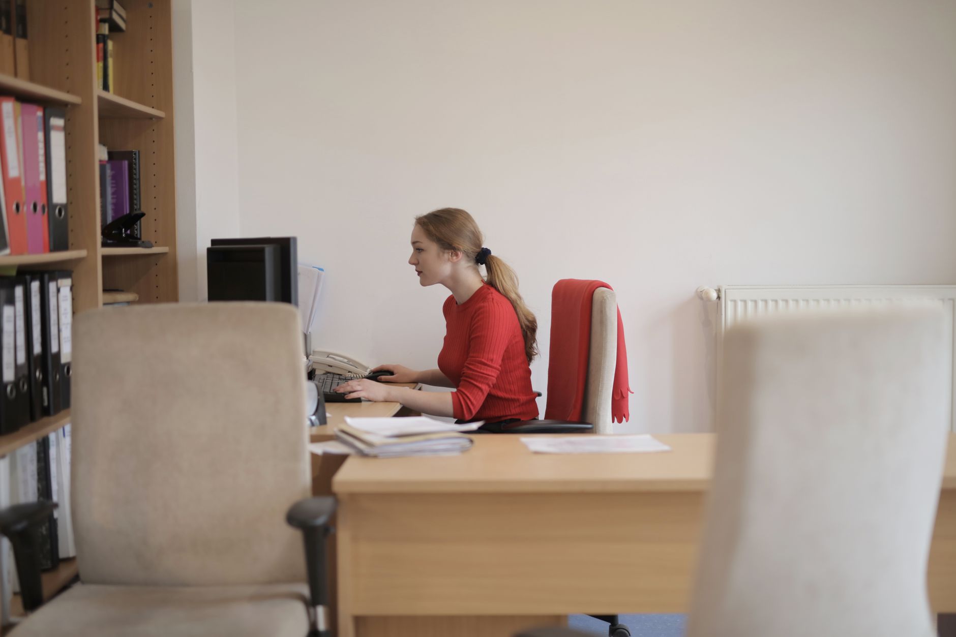 Side view of a woman concentrating on computer work in a contemporary office setting.